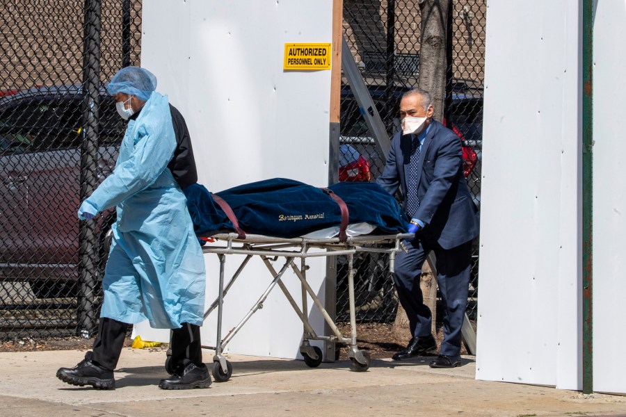 A funeral director and a Wycoff Heights Medical Center, employee transport a body, Wednesday, April 1, 2020, in New York. (AP Photo/Mary Altaffer)