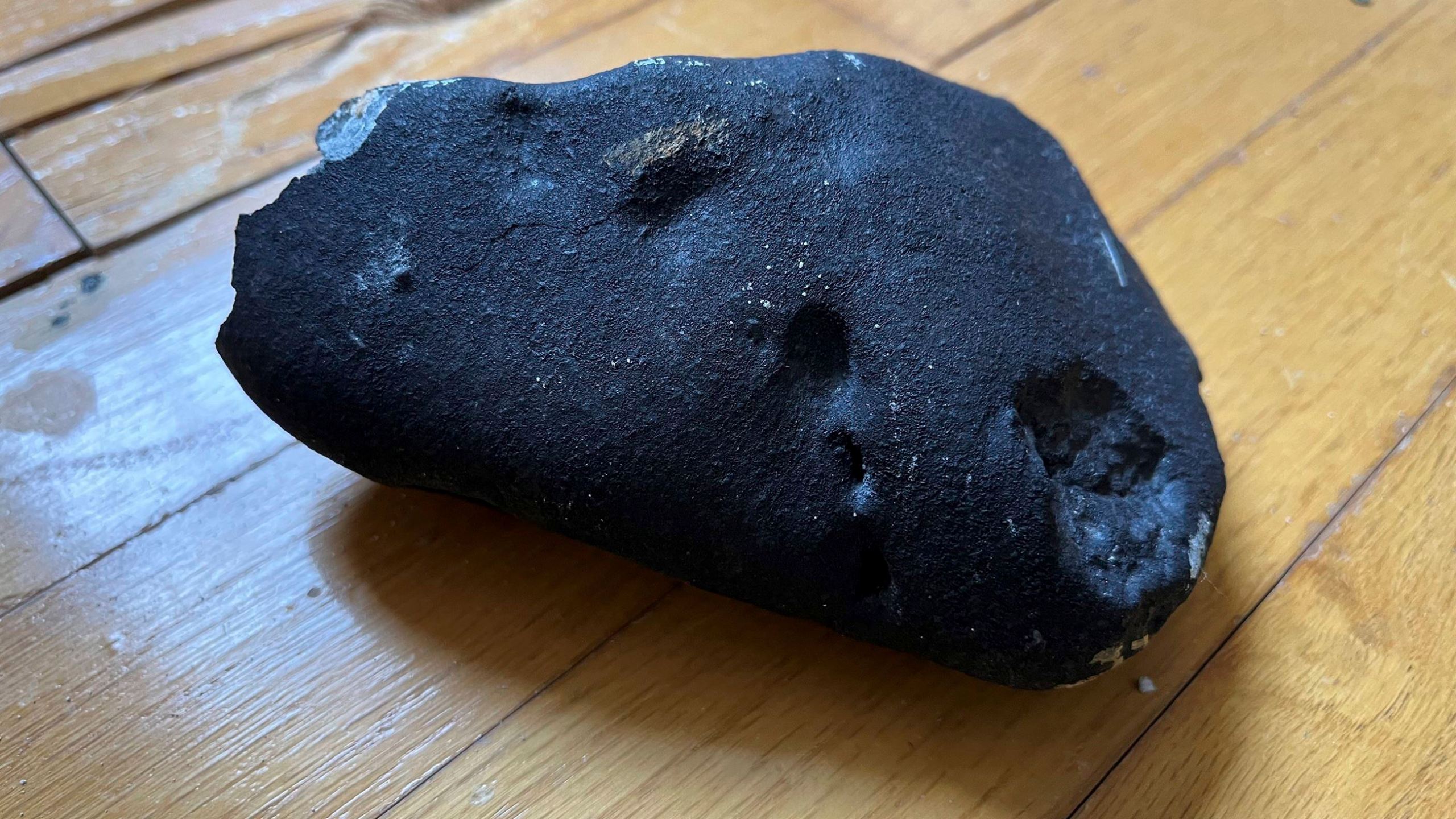 This image provided by Hopewell Township Police Department shows a metallic object believed to be a meteorite that struck the roof a residence in Hopewell Township, N.J. Hopewell Township police said the 4- by-6-inch, oblong-shaped object struck the ranch-style home on Monday, May 8, 2023 and eventually came to rest on a floor. It's estimated to weigh about four pounds. (Hopewell Township Police Department via AP)
