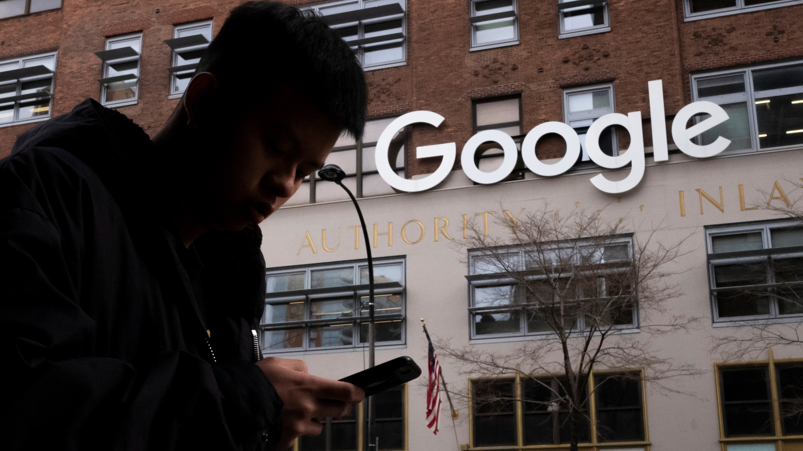 FILE - A man using a cellphone walks past Google offices on Dec. 17, 2018, in New York. On Tuesday, May 9, 2023, Maryland's highest court reversed a ruling by a lower court that the state's first-in-the-nation tax on digital advertising was unconstitutional, saying the court lacked jurisdiction over the case. (AP Photo/Mark Lennihan, File)