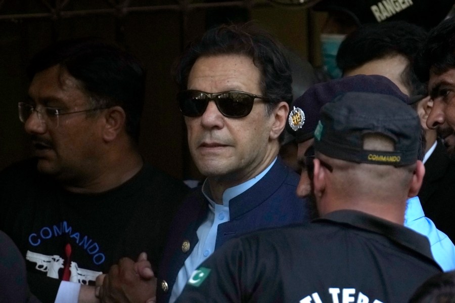 Pakistan's former Prime Minister Imran Khan, center, is escorted by security officials as he arrive to appear in a court, in Islamabad, Pakistan, Friday, May 12, 2023. A high court in Islamabad has granted Khan a two-week reprieve from arrest in a graft case and granted him bail on the charge. (AP Photo/Anjum Naveed)