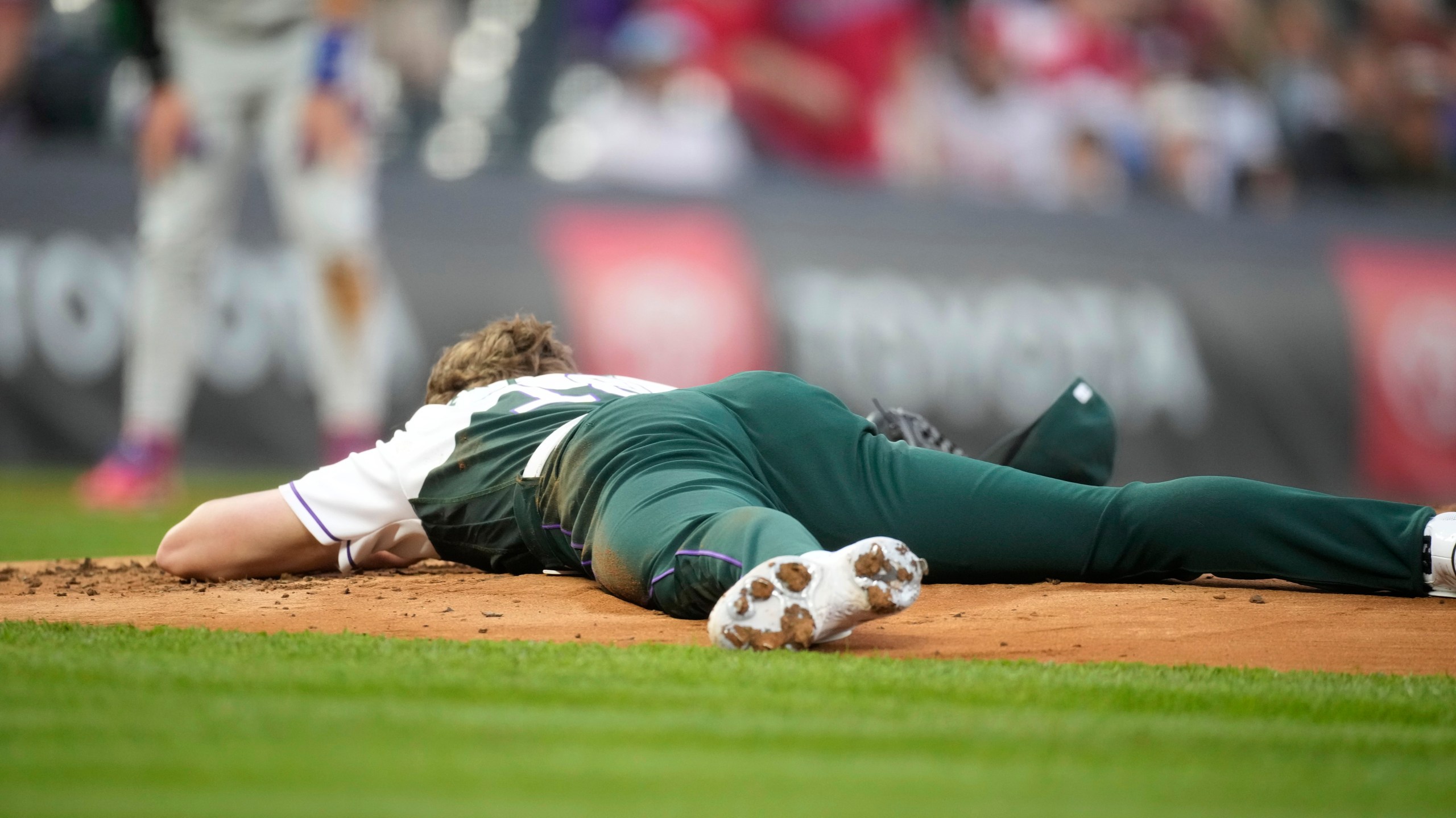 Colorado Rockies starting pitcher Ryan Feltner lies on the mound after getting hit by a single by Philadelphia Phillies' Nick Castellanos during the second inning of a baseball game Saturday, May 13, 2023, in Denver. (AP Photo/David Zalubowski)