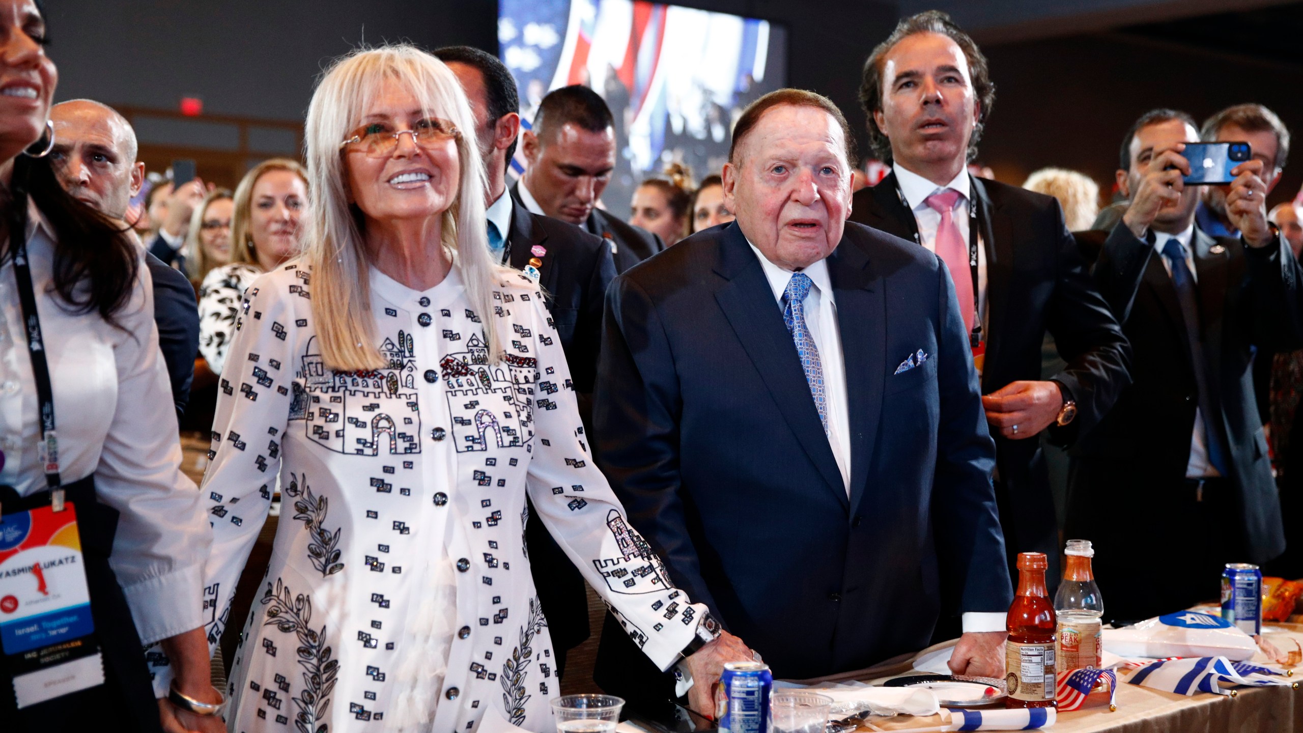 FILE - Las Vegas Sands Corporation Chief Executive and Republican mega donor Sheldon Adelson, center, and his wife, Miriam Adelson, left, listen as President Donald Trump speaks at the Israeli American Council National Summit in Hollywood, Fla., Saturday, Dec. 7, 2019. Miriam Adelson, the controlling shareholder of casino company Las Vegas Sands Corp., plans to sell $2 billion in company stock and buy an unspecified professional sports franchise, the company announced Tuesday, Nov. 28, 2023. Dallas Mavericks owner Mark Cuban is working on a deal to sell a majority stake in the NBA franchise to the Adelson family, a person with knowledge of the talks said late Tuesday. (AP Photo/Patrick Semansky, File)