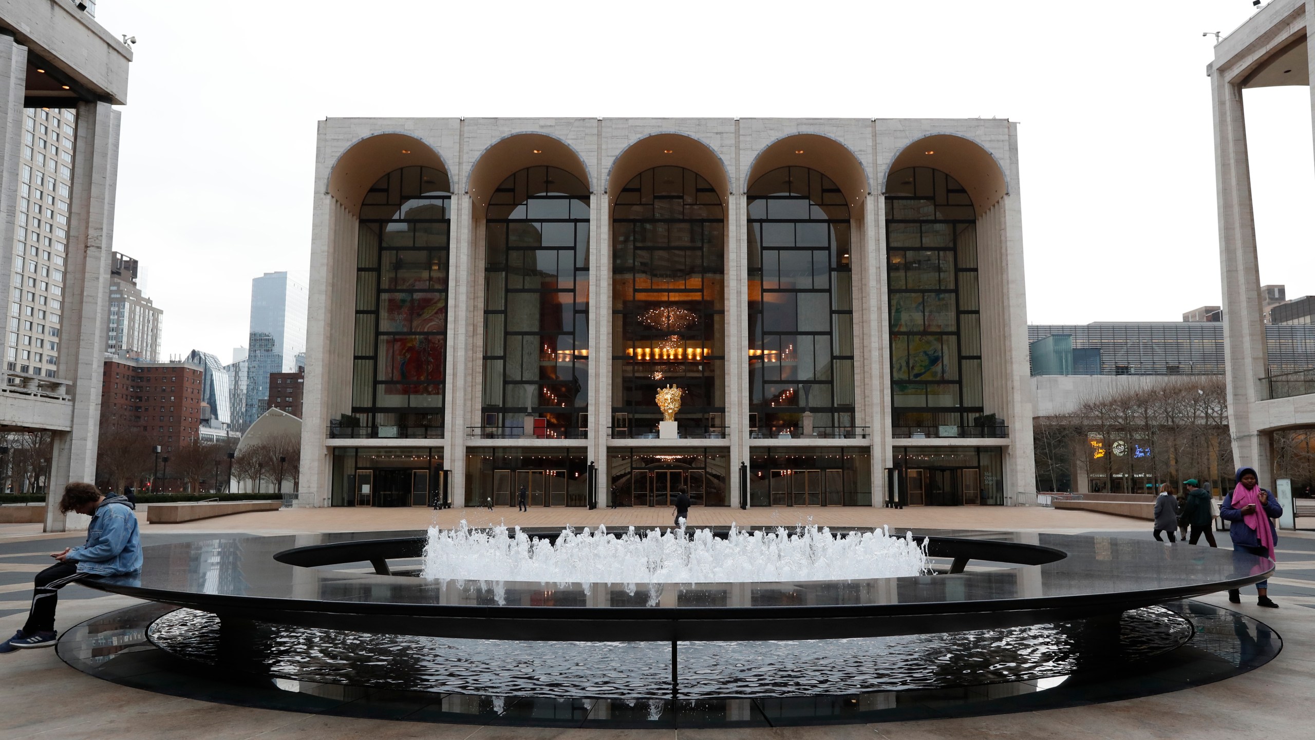 FILE - People appear in Josie Robertson Plaza in front of The Metropolitan Opera house at Lincoln Center in New York on March 12, 2020. . (AP Photo/Kathy Willens, File)