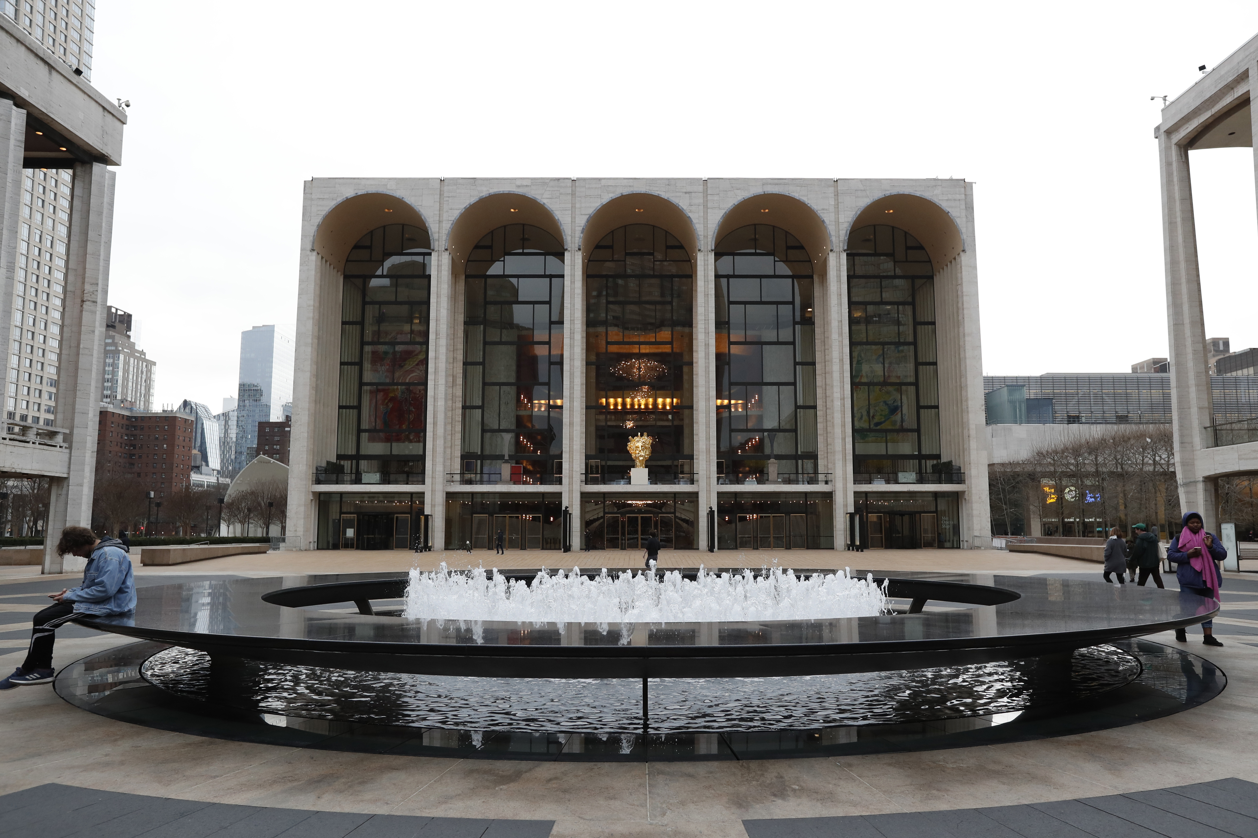 FILE - People appear in Josie Robertson Plaza in front of The Metropolitan Opera house at Lincoln Center in New York on March 12, 2020. . (AP Photo/Kathy Willens, File)