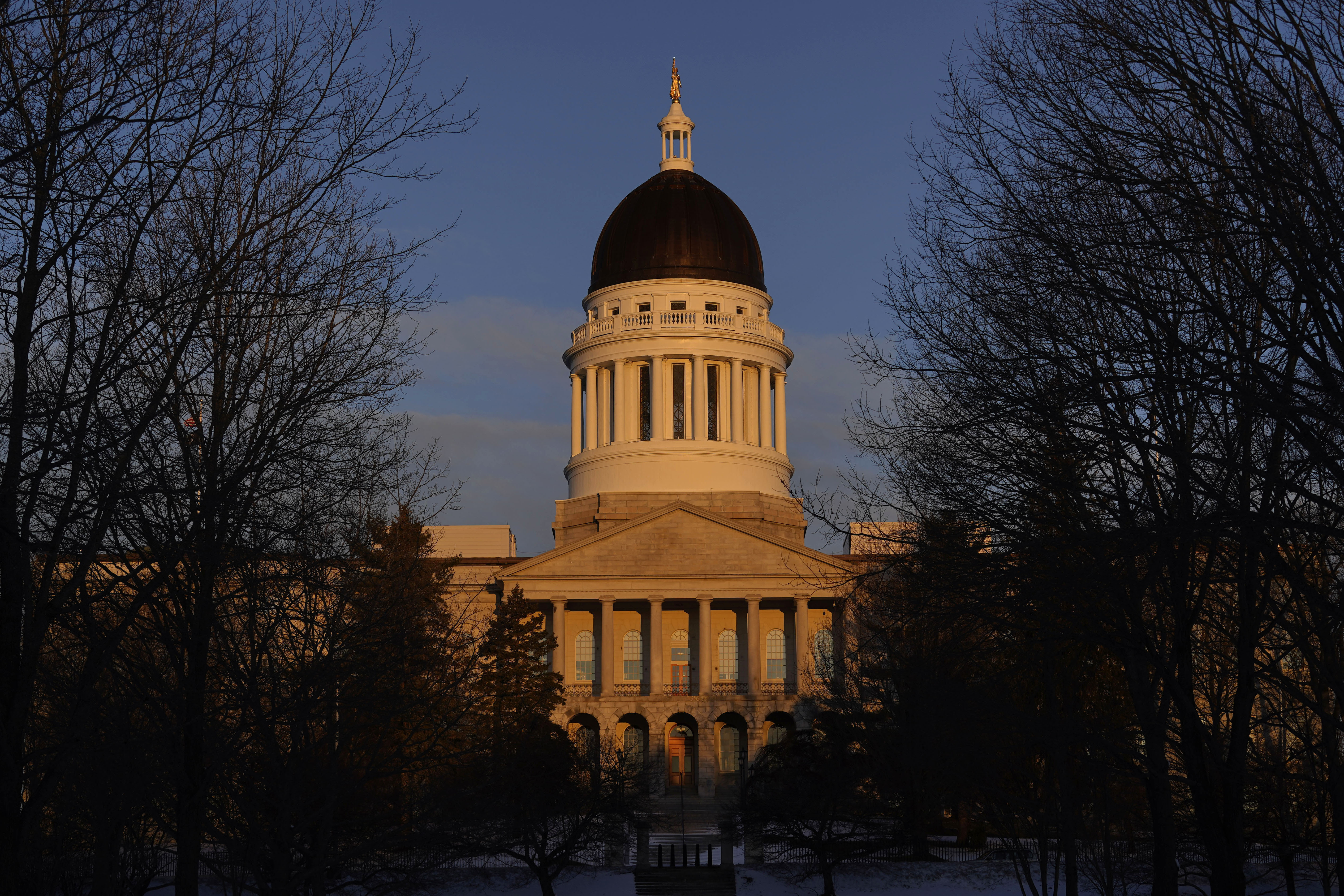 FILE - The Maine State House is seen at sunrise, March 16, 2023, in Augusta, Maine. Teachers and science advocates are voicing skepticism about a Maine proposal to update science education standards to incorporate teaching about genocide, eugenics and the Holocaust because of concerns about adequate teacher training and the nuanced nature of the material. The Maine Department of Education is performing the update as part of a review of standards that is required every five years. The proposed updates would have to ultimately be approved by a committee of the Maine Legislature. (AP Photo/Robert F. Bukaty, File)